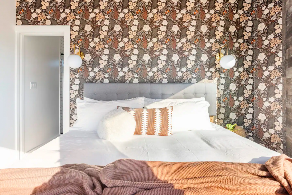 The Hex bedroom with floral wallpaper and rustic wood walls in the Texas Hill Country