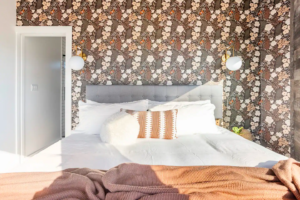 The Hex bedroom with floral wallpaper and rustic wood walls in the Texas Hill Country